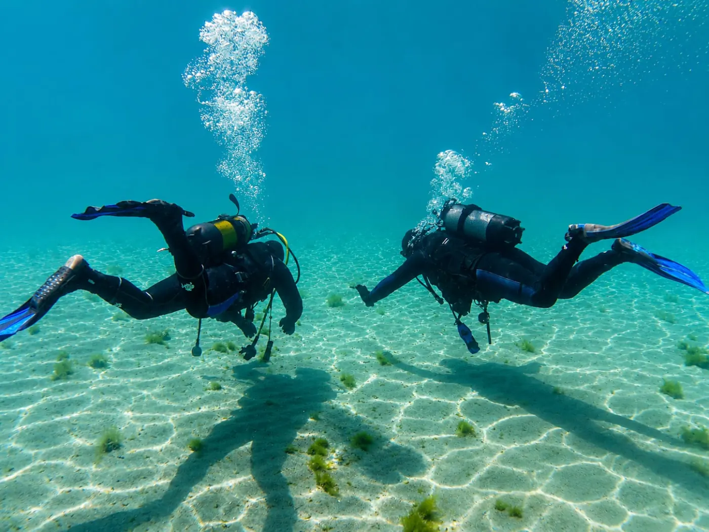 Two scuba divers gliding over the clean sandy floor of Lake Ohrid, North Macedonia