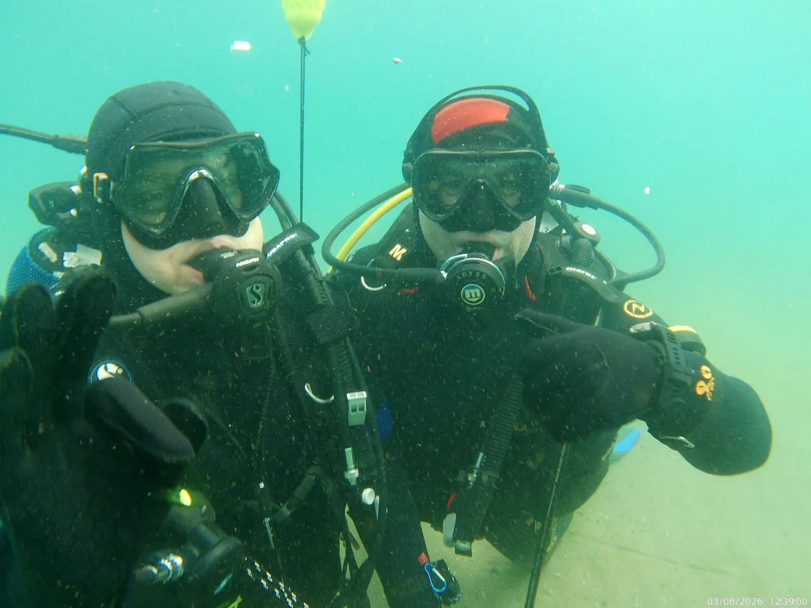Two scuba divers below the surface of Lake Ohrid wearing masks and regulators